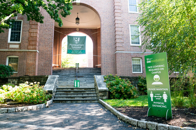 Photograph of Manhattan College entrance to Quad with signage about social distancing (six feet apart)